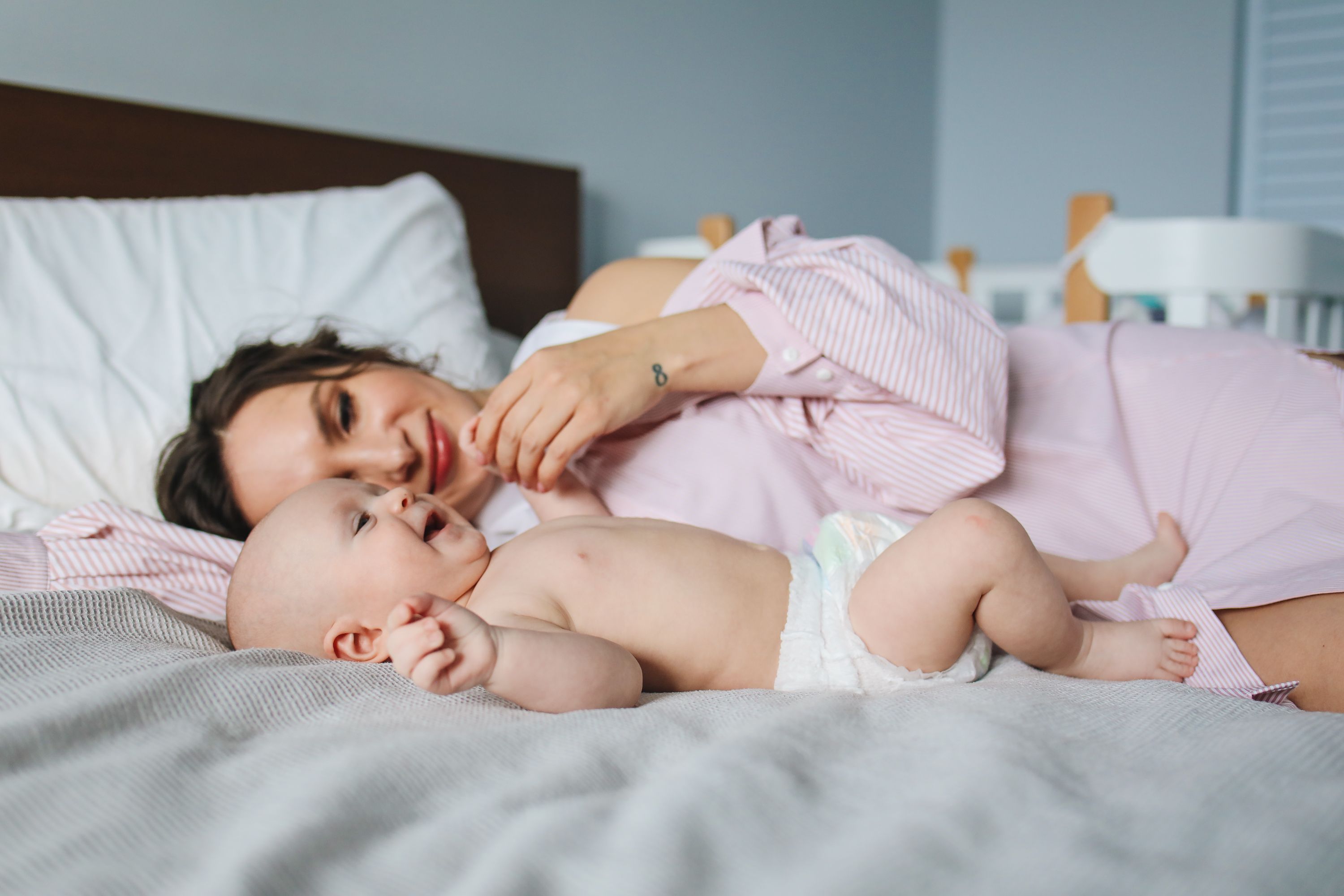 Mãos entrelaçadas repousando sobre uma barriga grávida em luz suave